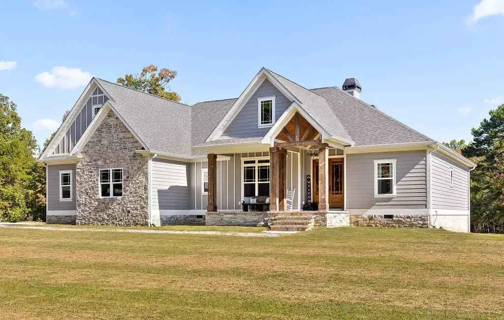 Front of a gray one-story home with a stone gable and a timber-framed entry porch